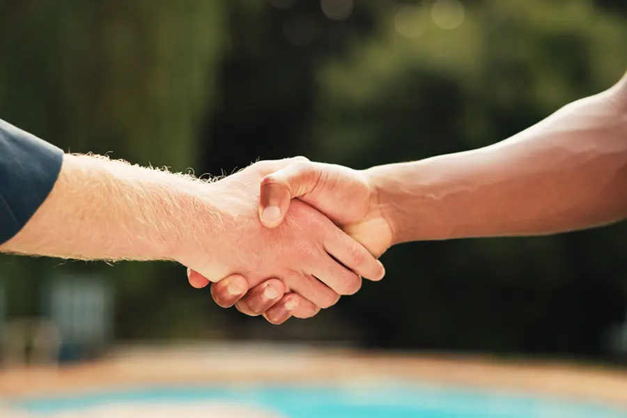 Two people shaking hands with pool background